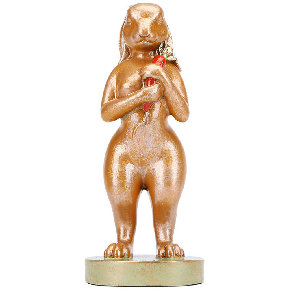 Golden rabbit statue in a standing pose holding a red accent, a symbol of good luck for home decor, placed on a greenish base against a brown background 03