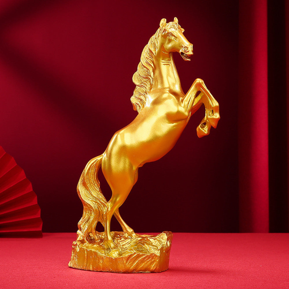 Golden rearing horse statue with a polished finish, a Feng Shui symbol of good fortune and strength, displayed as elegant home decor against a red background