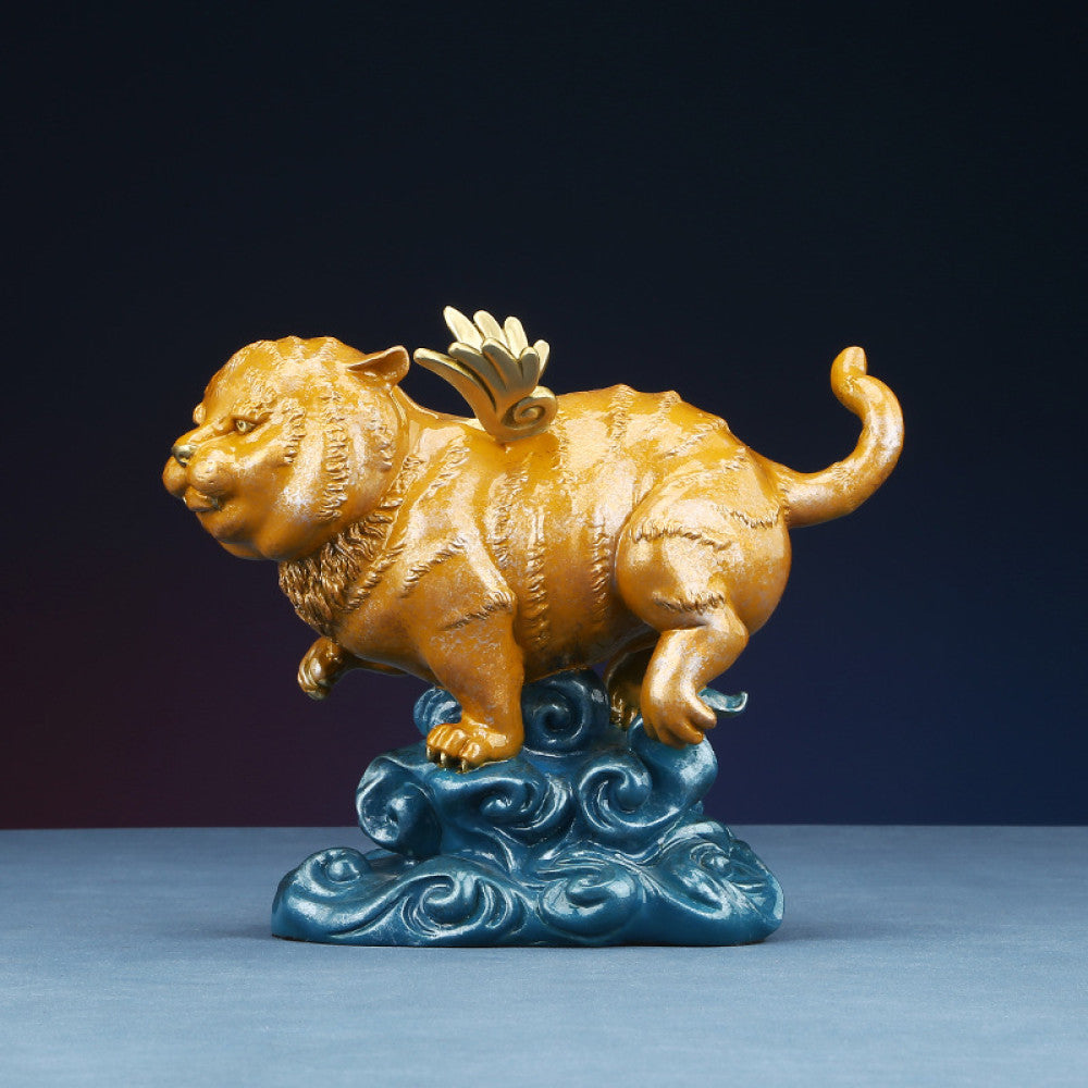 Golden winged tiger statue with blue cloud base, a Feng Shui symbol of strength and good fortune, displayed as elegant home decor against a dark background