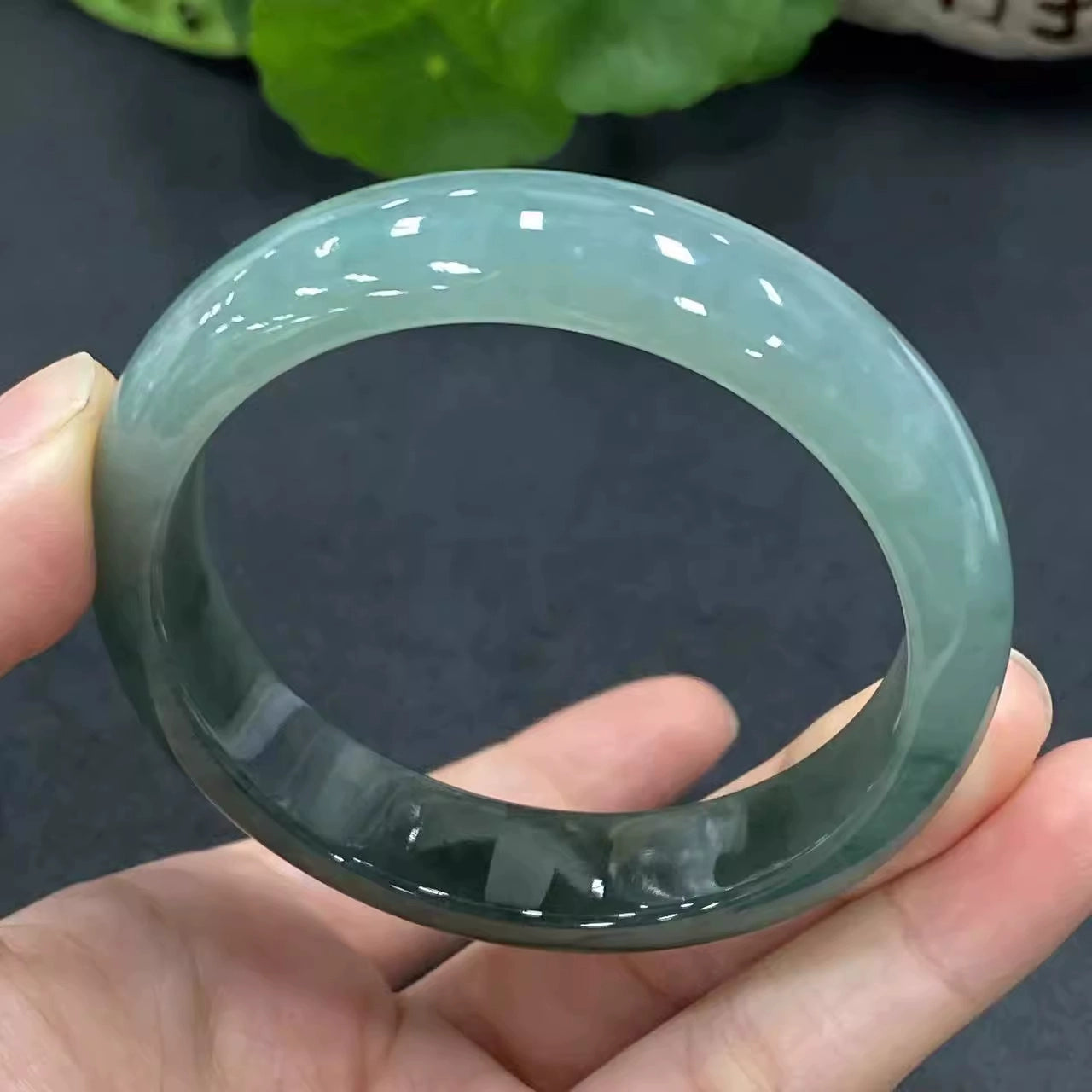 Hand holding icy green natural jade bangle, high translucency jade jewelry 01