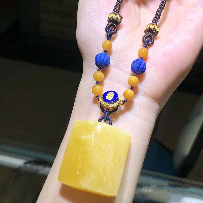 A stunning handmade necklace showcasing a large, beautiful amber pendant, complemented by turquoise beads, white shell - like beads and gold - toned decorative elements, all strung on a dark braided cord. Ideal for those who love unique and elegant jewelry pieces. 05