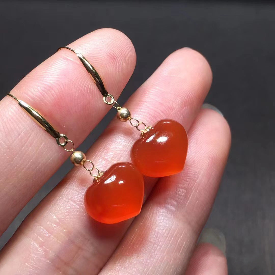 Red agate heart-shaped earrings, paired with 18K gold accessories, presenting a charming luster on the fingers