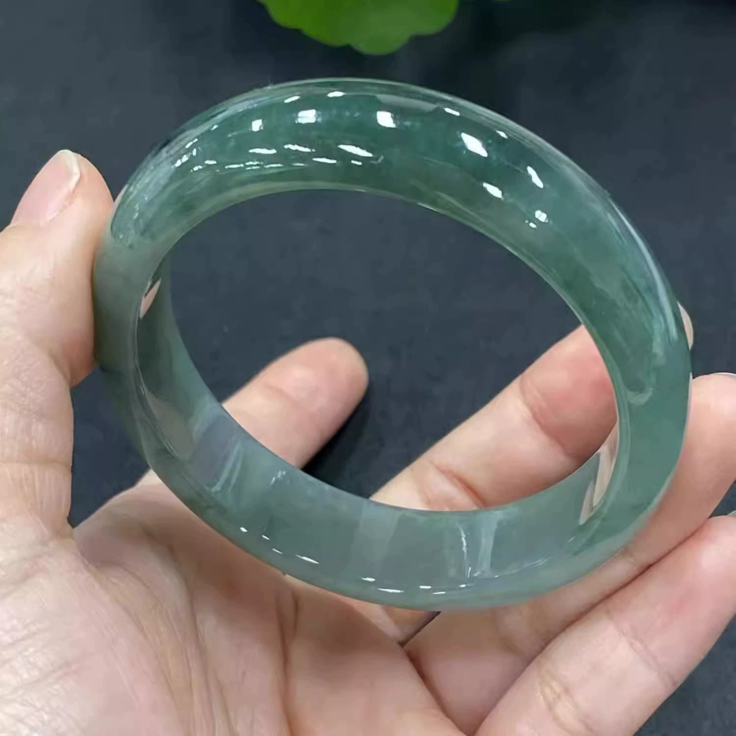 Hand holding icy green natural jade bangle, high translucency jade jewelry