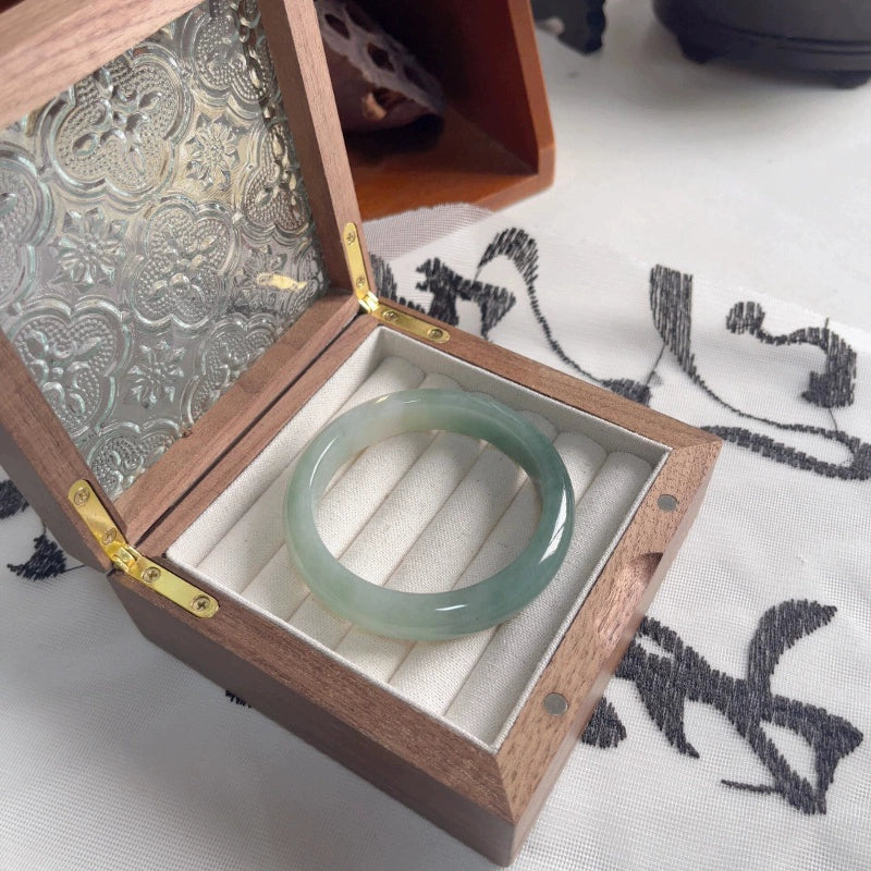Icy green natural jade bangle inside an ornate wooden jewelry box, showcasing Chinese jade jewelry