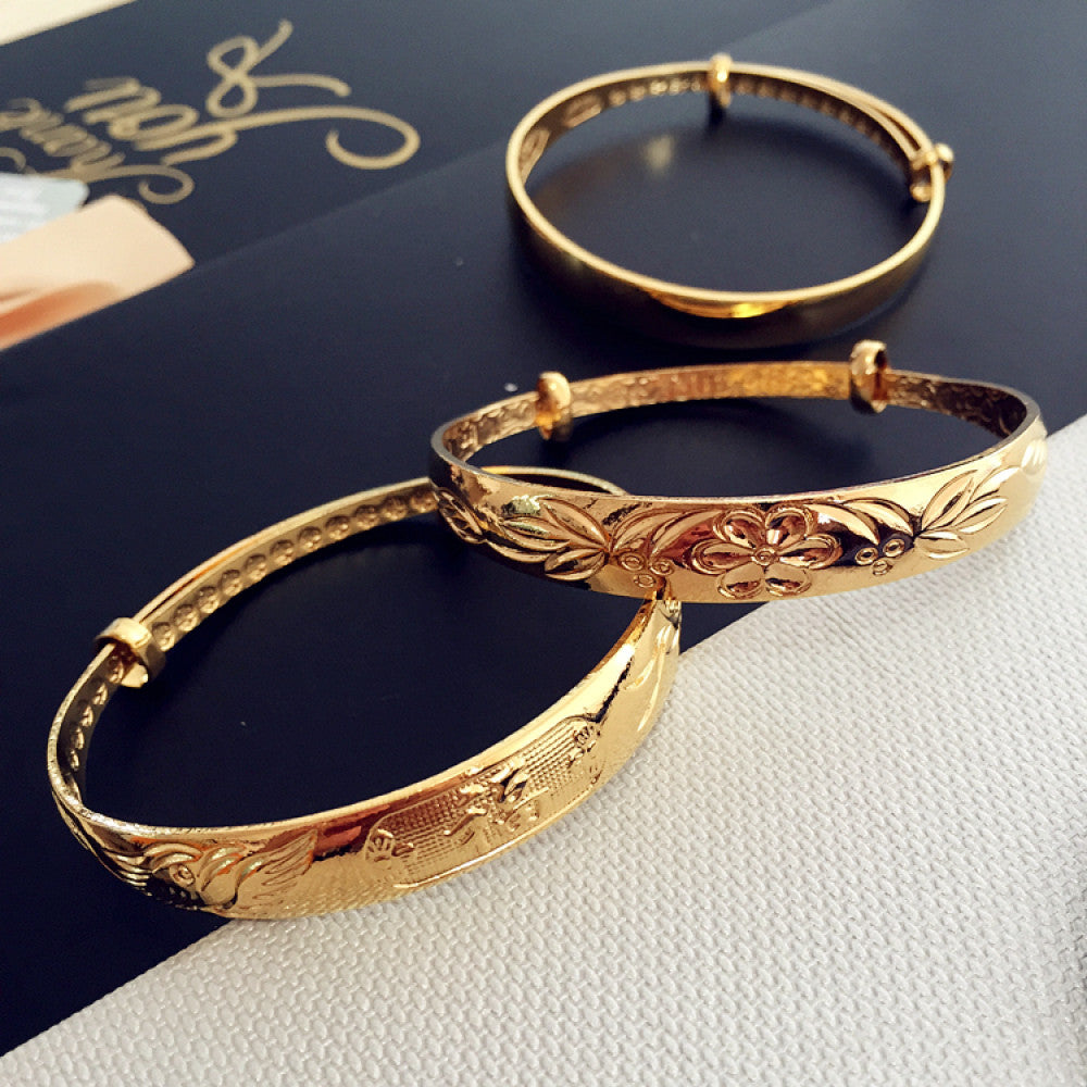 Luxury gold-tone bangle set with engraved floral and sleek designs, displayed on gift packaging with a bow, ideal for luxury fashion and gifting enthusiasts 01