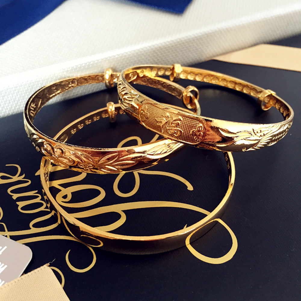 Luxury gold-tone bangle set with engraved floral and sleek designs, displayed on gift packaging with a bow, ideal for luxury fashion and gifting enthusiasts 03