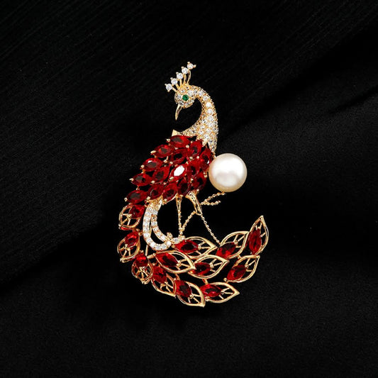 This opulent brooch showcases a majestic peacock design, crafted with a gleaming gold-tone metal base. The peacock’s body and elaborate tail are lavishly adorned with vibrant emerald-cut green crystals, while its head and neck are encrusted with sparkling clear crystals. A large, lustrous white pearl rests gracefully beside the peacock, adding a touch of timeless elegance. Perfect for elevating formal attire, evening gowns, or special occasion outfits, this statement piece exudes luxury and intricate