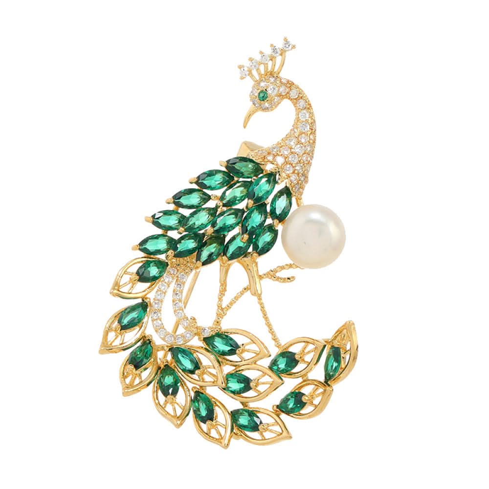 This opulent brooch showcases a majestic peacock design, crafted with a gleaming gold-tone metal base. The peacock’s body and elaborate tail are lavishly adorned with vibrant emerald-cut green crystals, while its head and neck are encrusted with sparkling clear crystals. A large, lustrous white pearl rests gracefully beside the peacock, adding a touch of timeless elegance 05