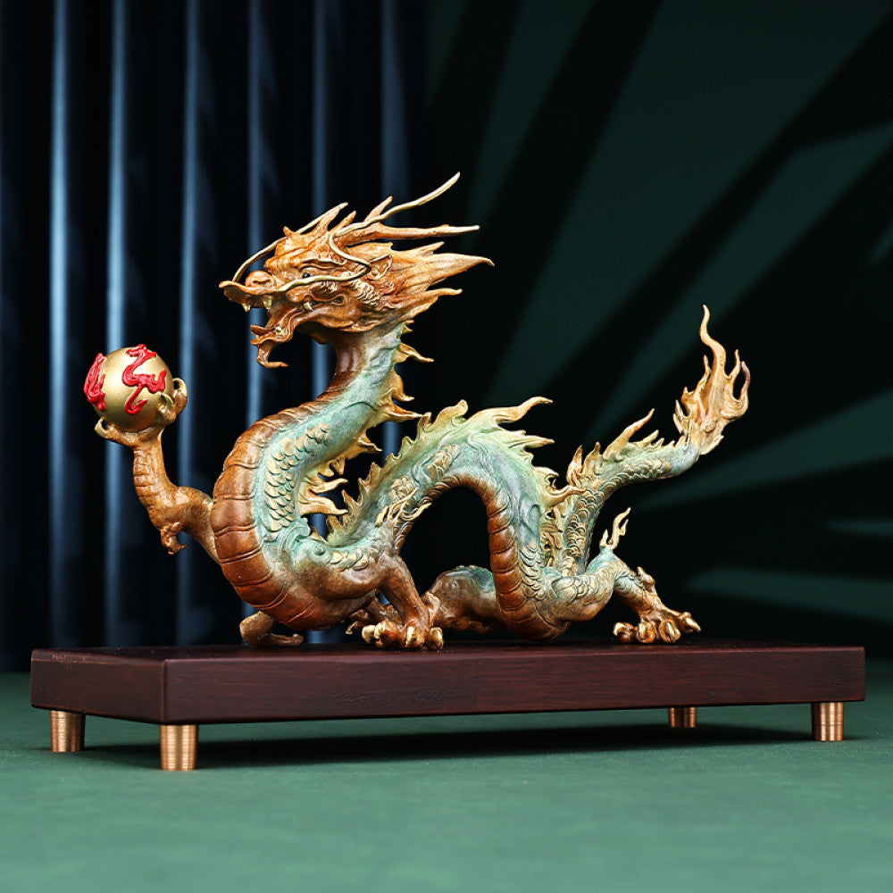 Colorful Chinese dragon statue with a red pearl, a Feng Shui symbol of good fortune and strength, displayed on a wooden base as elegant home decor against a dark background