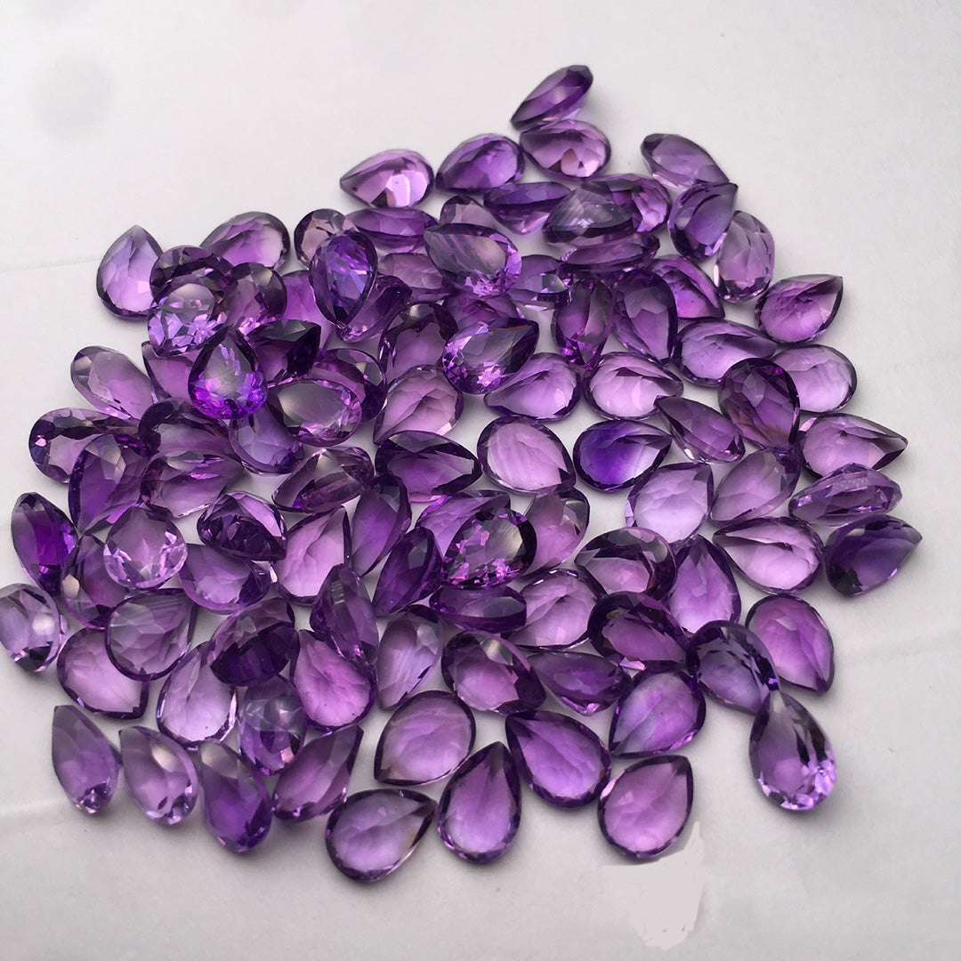 A teardrop-shaped amethyst on a white background, bright purple, suitable for jewelry setting