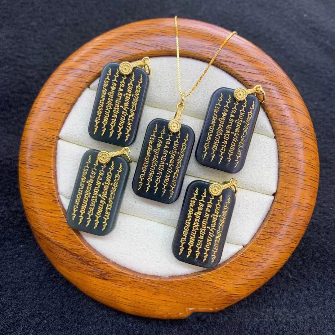 Set of natural black obsidian pendants featuring gold - inscribed mantras, each attached to a gold - plated chain. Displayed on a round wooden jewelry tray with a soft, white - cushioned interior.