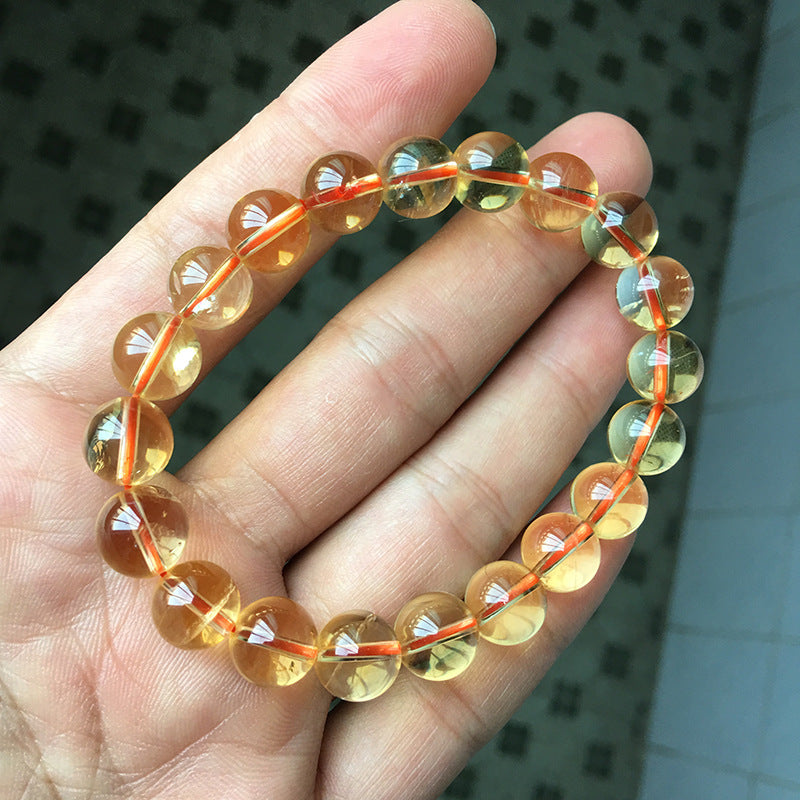 A natural citrine bead bracelet held in a hand, featuring transparent to translucent beads with a beautiful yellow - orange hue, strung together on an orange cord.