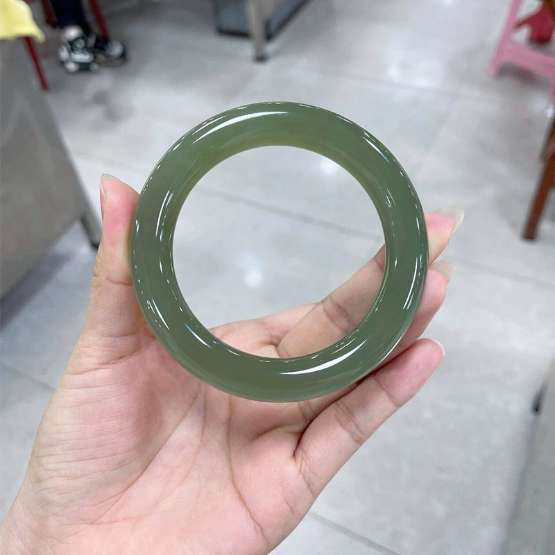 Hand holding natural deep green round jade bangle