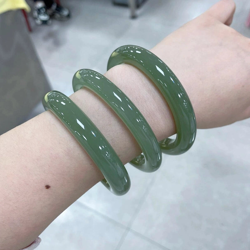 Hand holding natural deep green round jade bangle 01