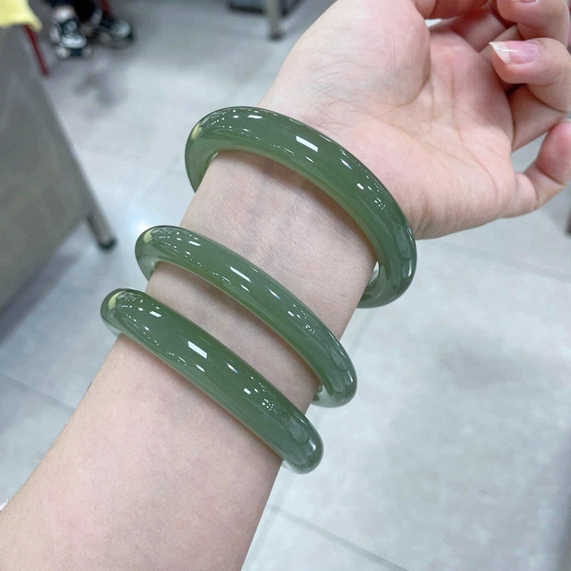 Hand holding natural deep green round jade bangle 02