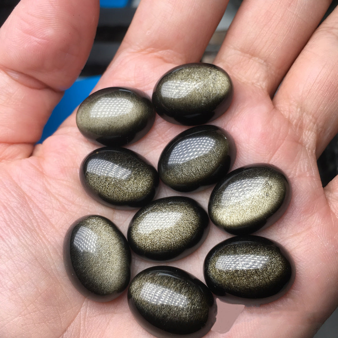 Elliptical gold obsidian rough stones, sparkling with golden flecks,
10 pieces displayed in the palm.