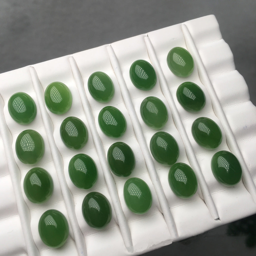 There are 22 oval jaspers on a white tray, with a warm texture and bright green color.