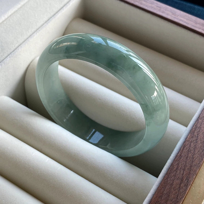 Wrist wearing natural icy blue-green jadeite bangle stacked with dark green gemstone bead bracelets 01