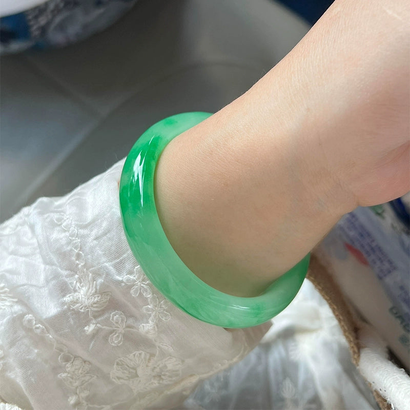 Hand wearing natural icy green jade bangle with white embroidery sleeve