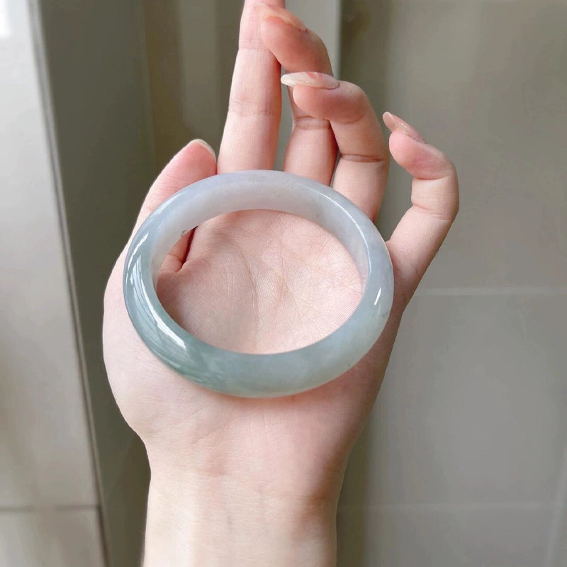 Hand holding natural icy lavender green jade bangle