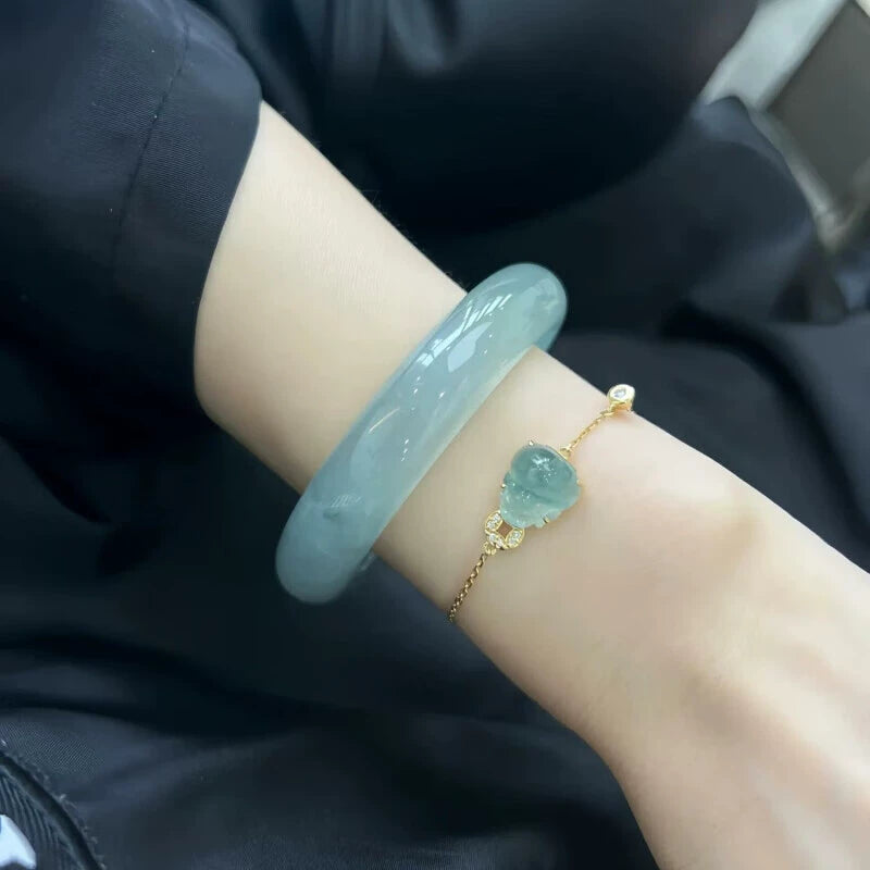 Wrist wearing natural icy light blue jadeite bangle and gold bracelet with heart-shaped aquamarine in elegant stacking style