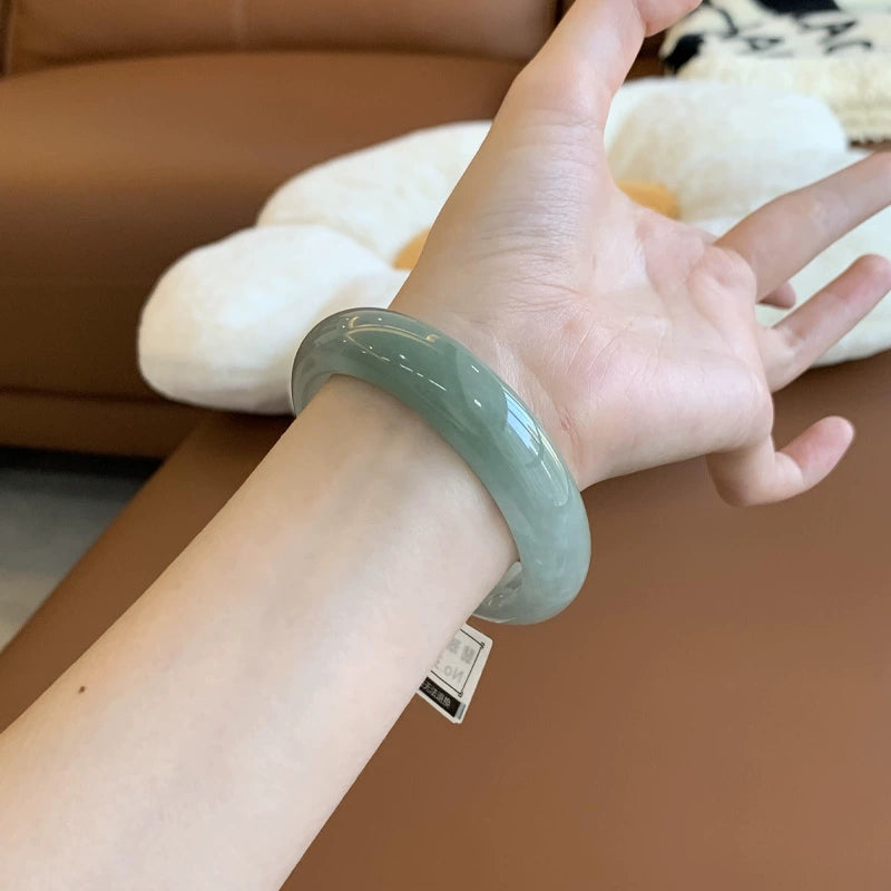 Hand holding natural icy light green jadeite bangle 01