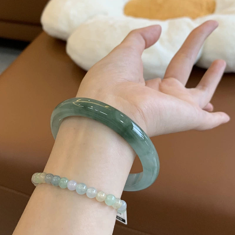Hand holding natural icy translucent green jade bangle 01