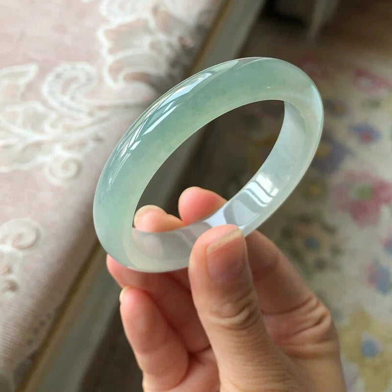 Hand holding natural icy translucent light green jadeite bangle 01