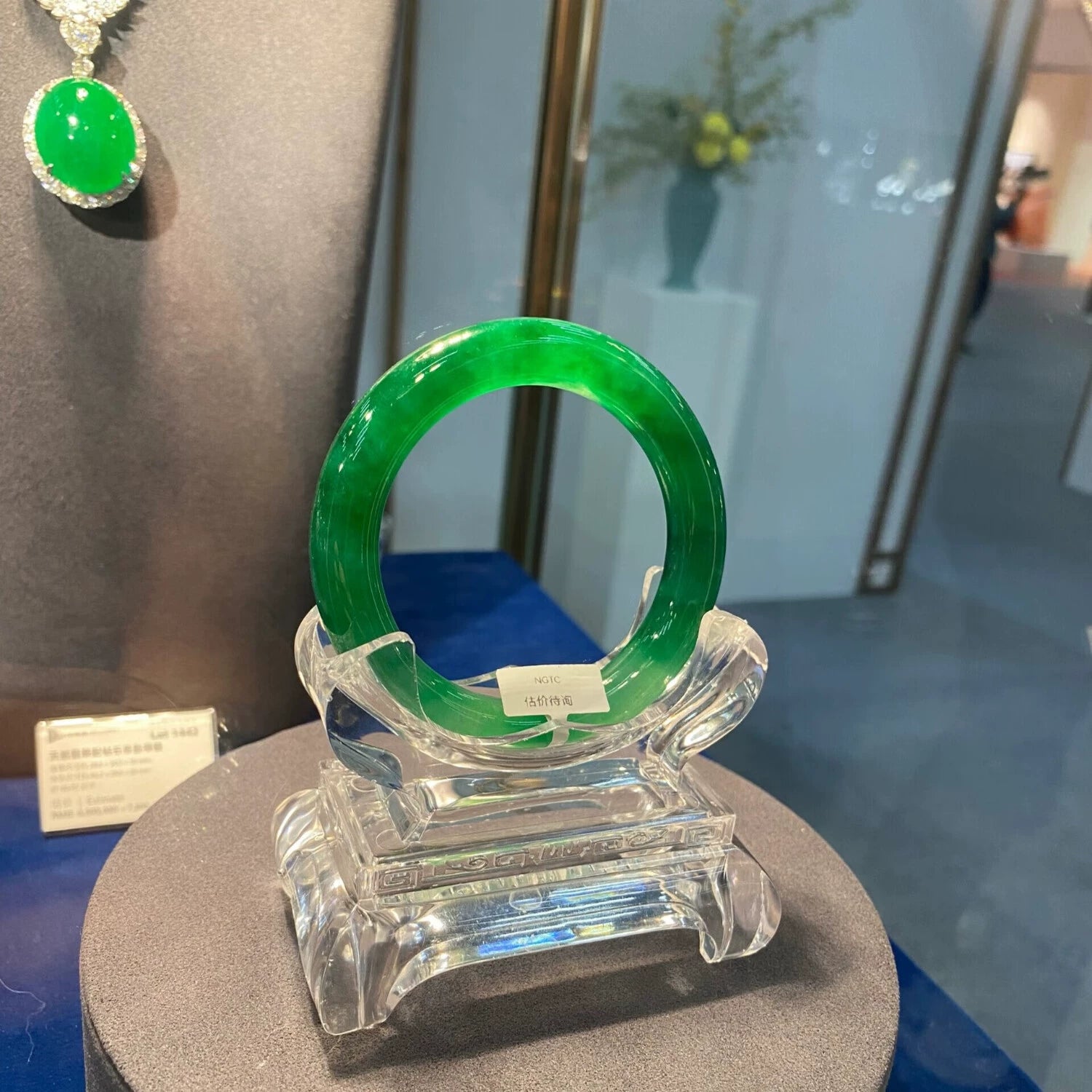 Natural imperial green icy jadeite bangle on clear display stand with price tag in jewelry exhibition