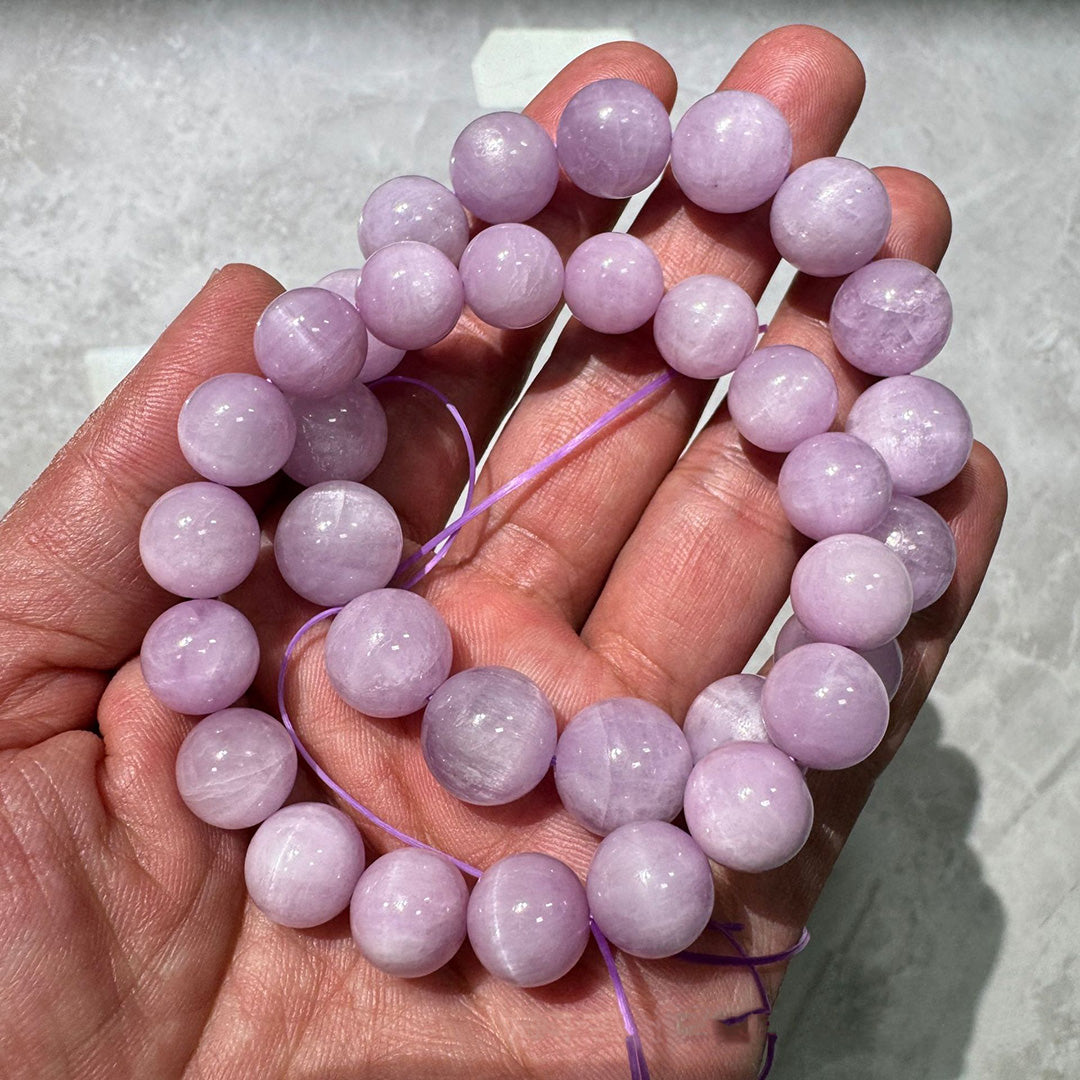 A hand - held natural rose quartz bead bracelet, showcasing smooth, round beads with a soft, translucent pink hue 01