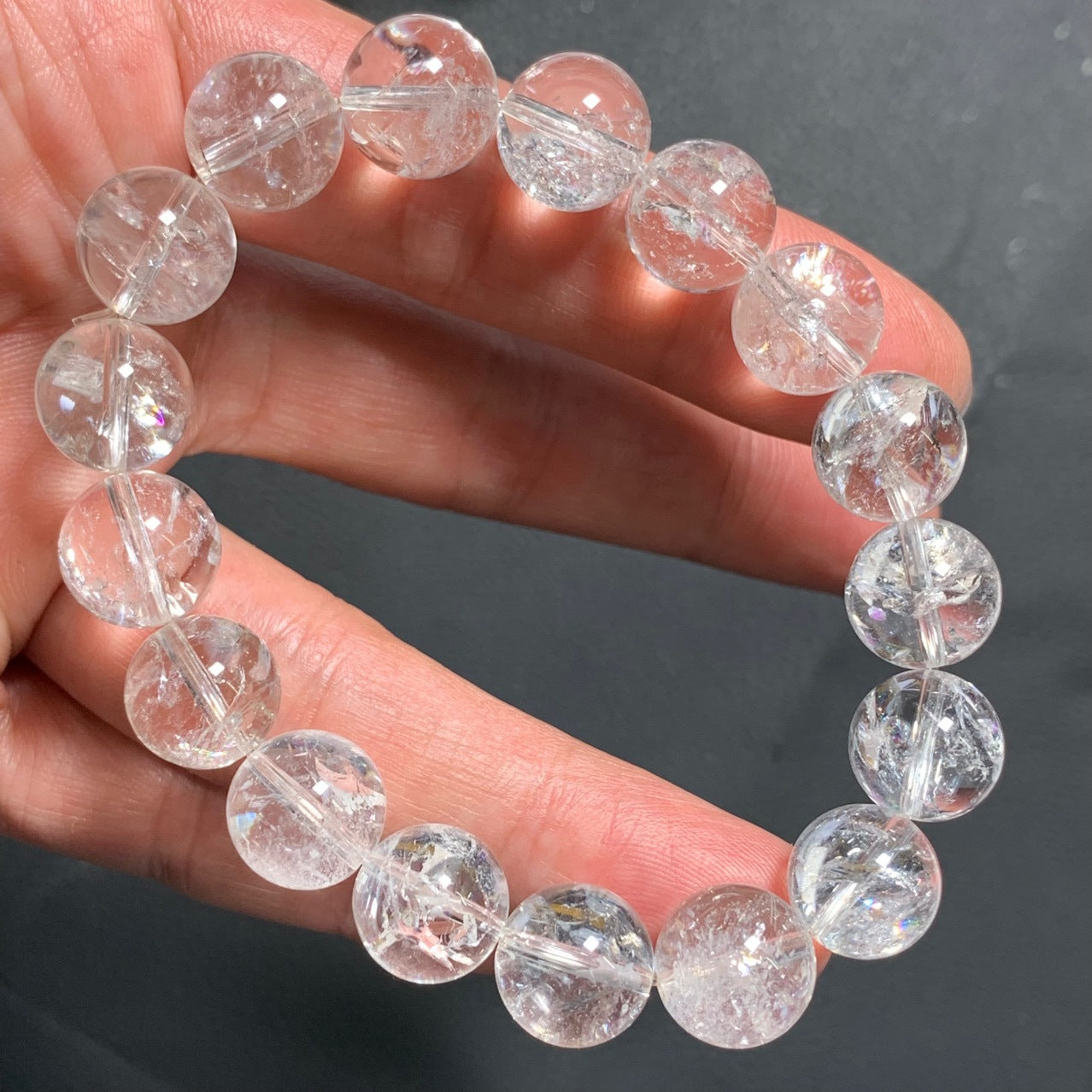 A hand - held natural rutilated quartz bead bracelet, featuring transparent beads with visible needle - like inclusions, creating a sparkling and unique visual effect.