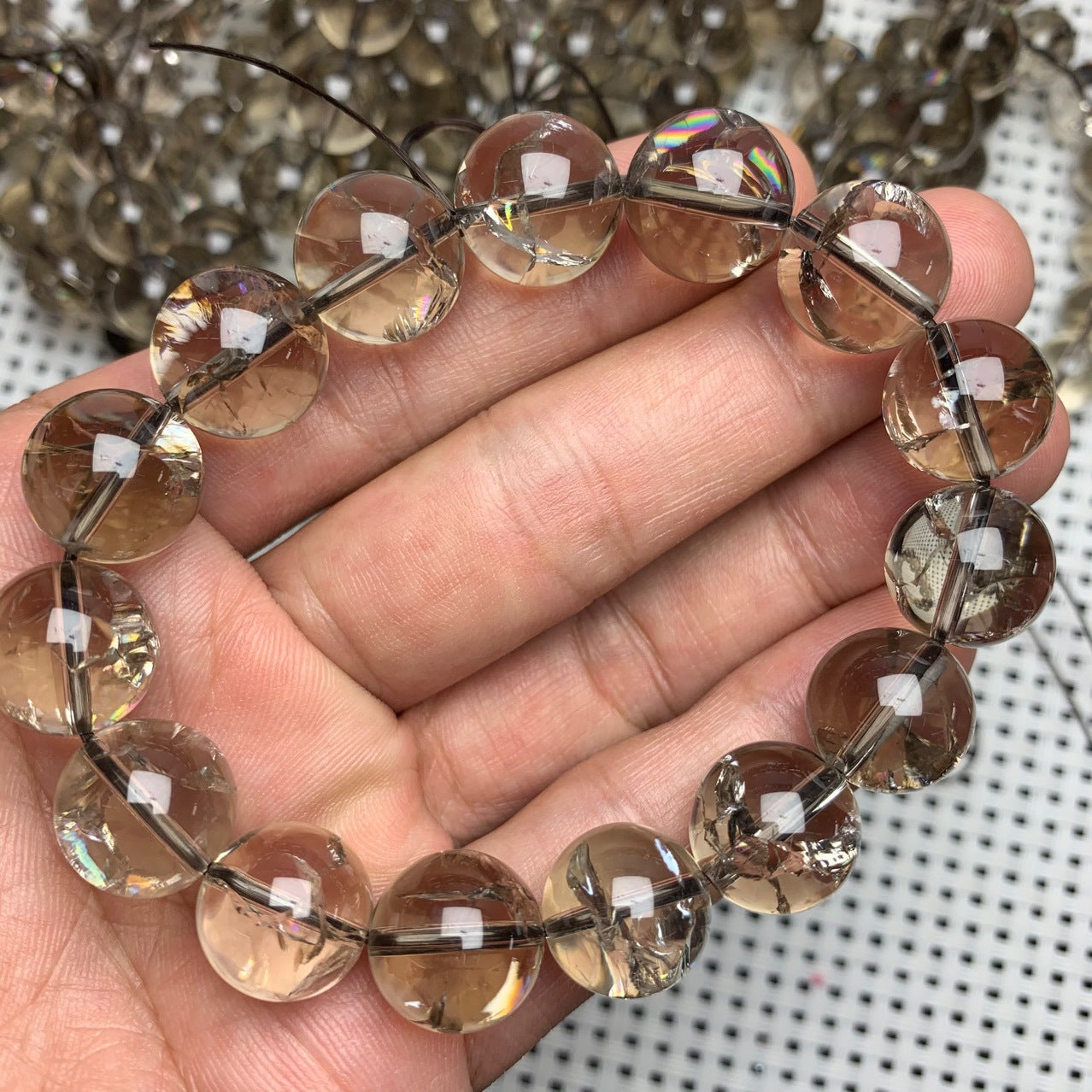 A natural smoky quartz bead bracelet held in a hand, showcasing semi - transparent beads with a beautiful smoky hue, strung together on a cord.