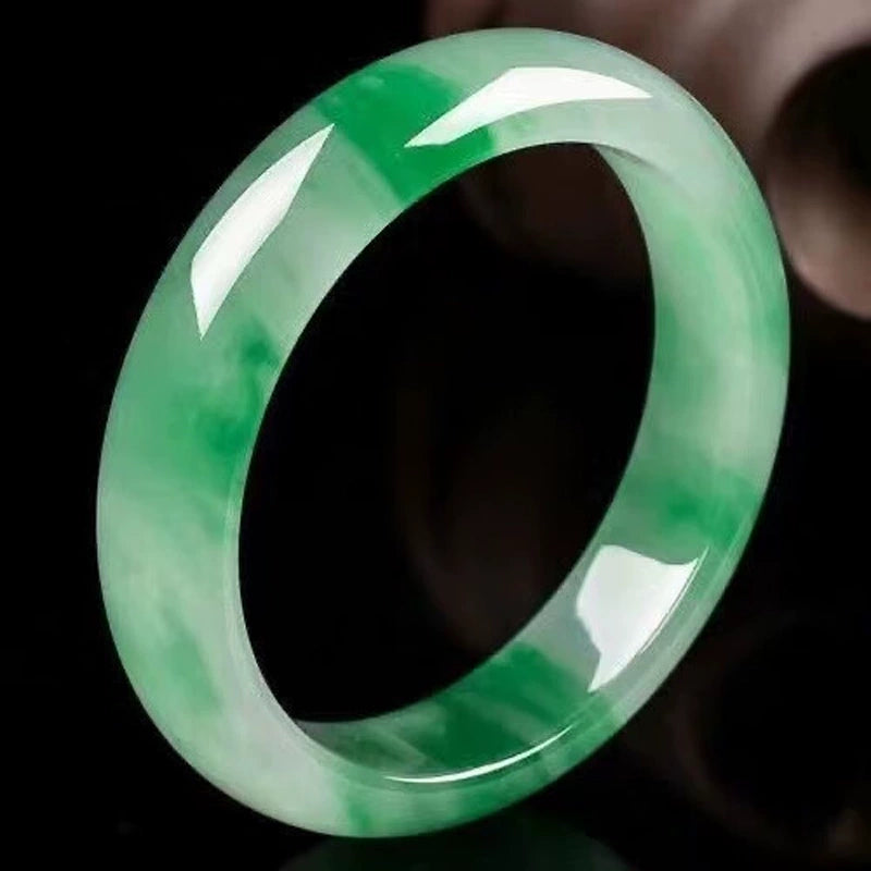 Natural vivid green gradient jadeite bangle against black background with glossy finish 01