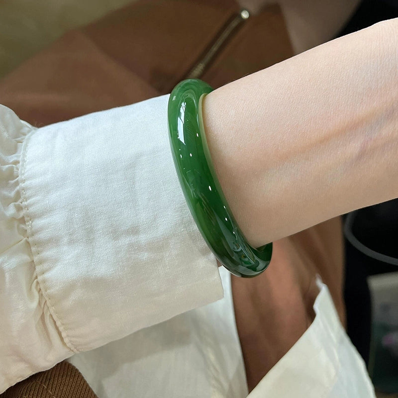 Hand wearing natural vivid green jadeite bangle with white cuff