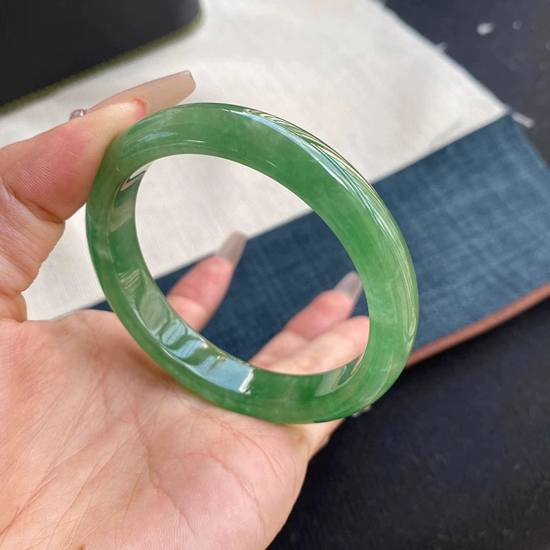 Hand holding natural vivid green jadeite bangle with fabric background 01