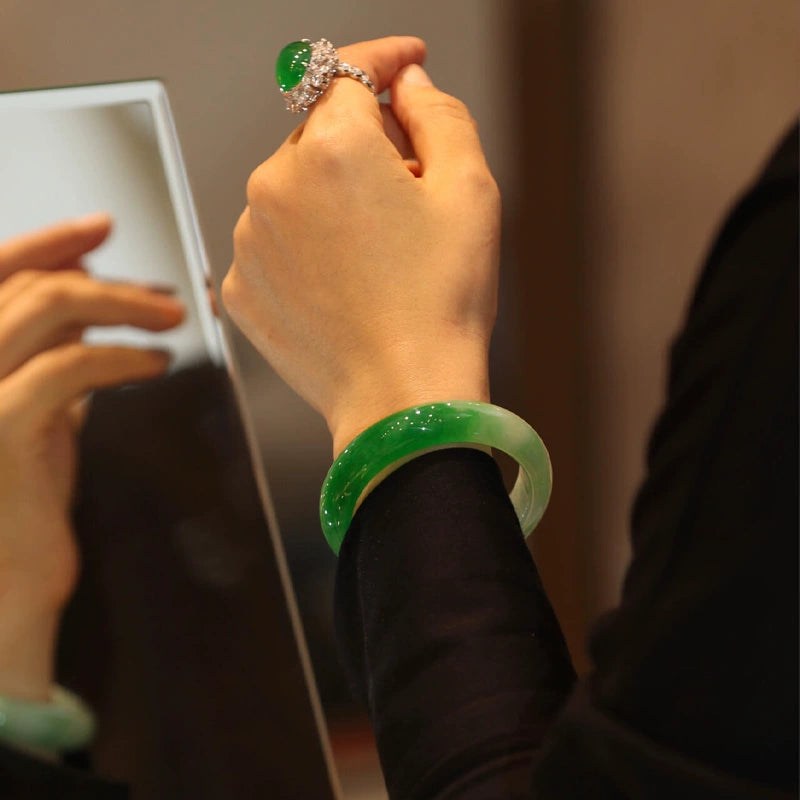 Hand wearing natural vivid green jadeite bangle and matching jadeite ring in jewelry store 01