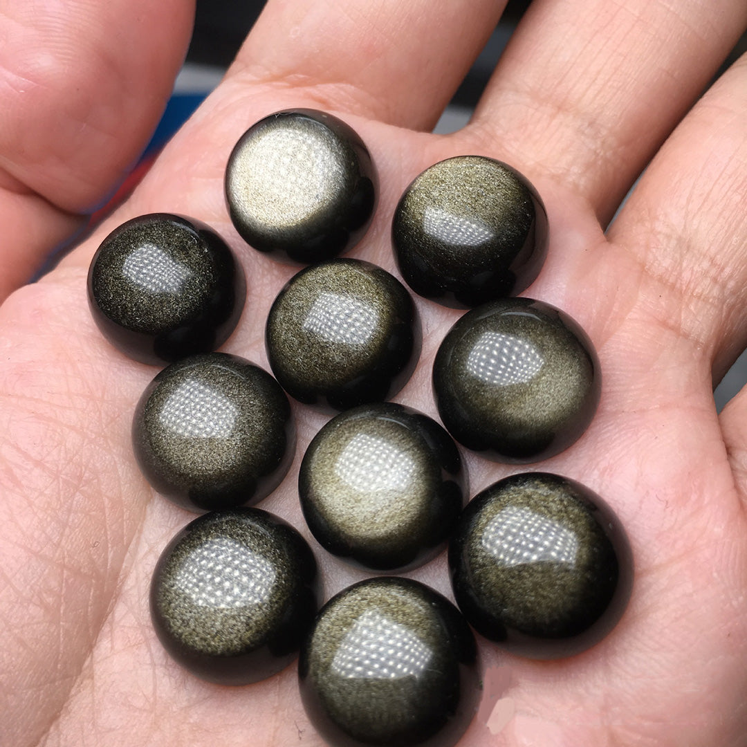 The round sunstone on the palm of the hand, with a black gold background and golden sand eyes, fully displays the charm of the gemstone.