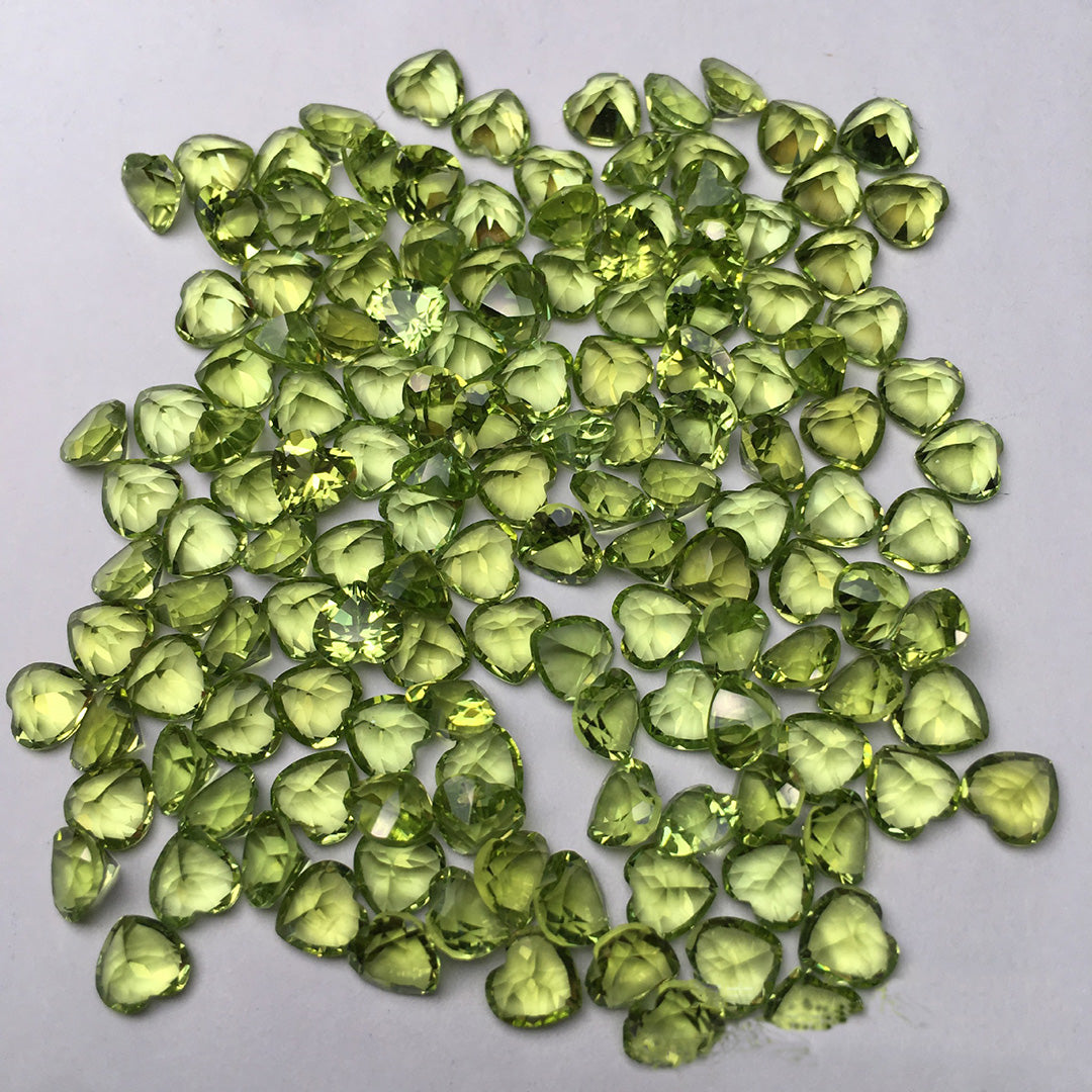 This heart-shaped peridot on a white background has a vibrant green color and is suitable for jewelry setting.