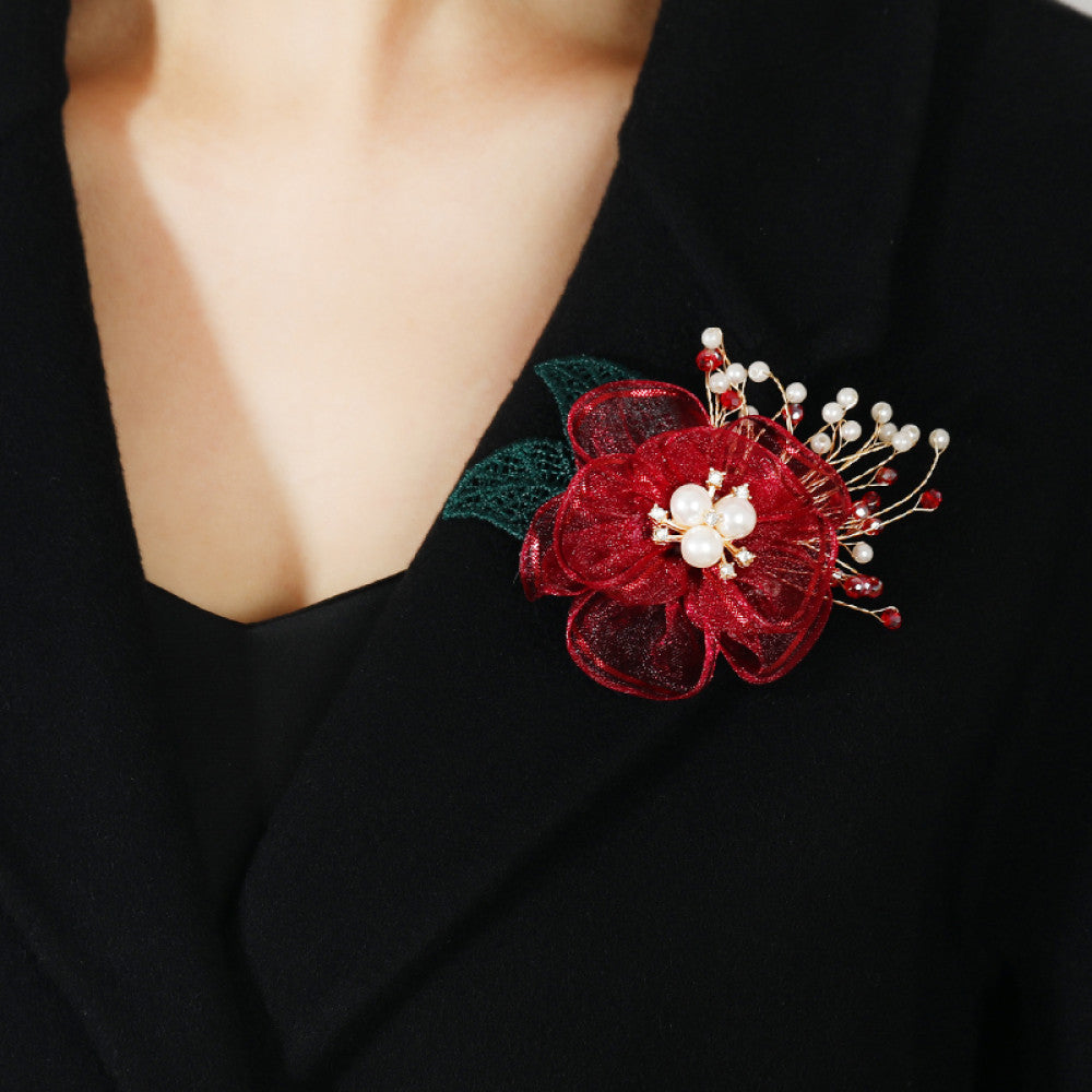 This elegant accessory features a layered navy tulle flower at its center, adorned with lustrous pearls and sparkling crystals. Delicate gold wire sprigs dotted with white and blue beads extend outward, complemented by a rich green lace leaf. Perfect for adding a touch of sophistication to evening gowns, blazers, or special occasion outfits, this piece blends delicate craftsmanship with timeless elegance. 05