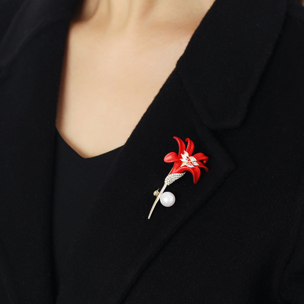 This elegant brooch features a vibrant red lily with a crystal-encrusted gold stem, accented by a lustrous pearl. A sophisticated floral accessory for any outfit 02