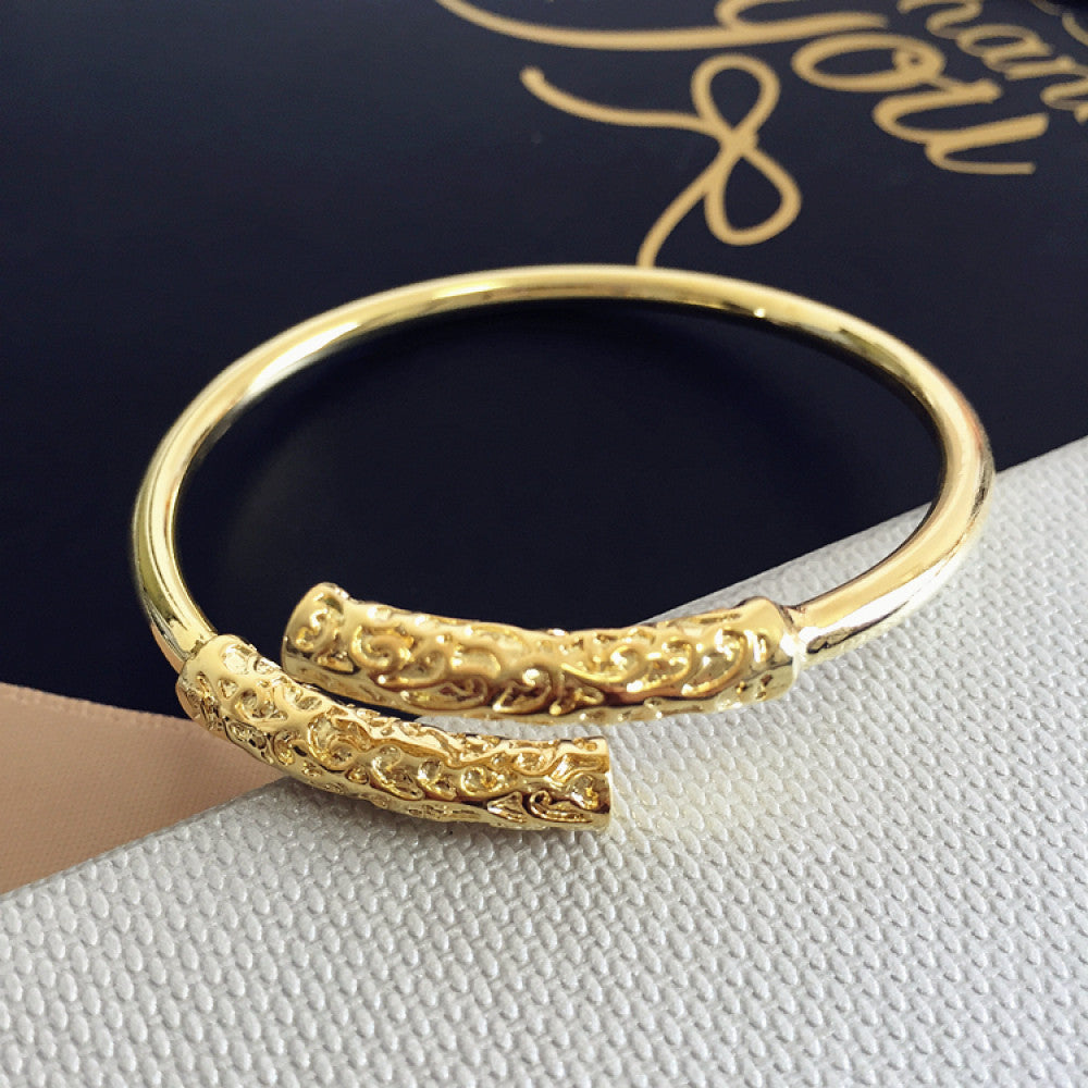 Rose gold plated bangle with engraved detail, displayed on textured surface, ideal for luxury fashion and minimalist jewelry enthusiasts 01