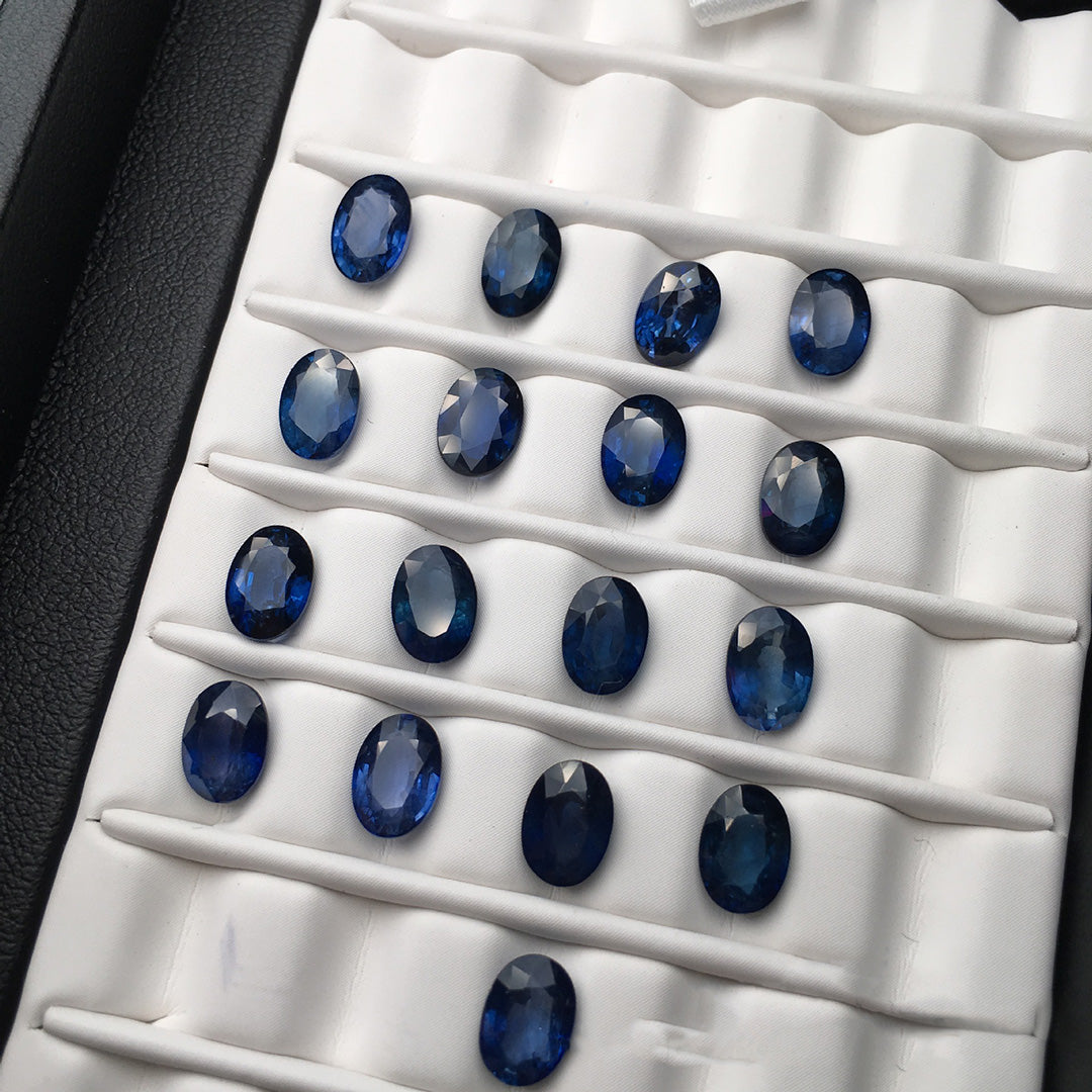 Oval sapphires on white mounts, rich deep blue color, multiple gemstones displayed in their raw state.