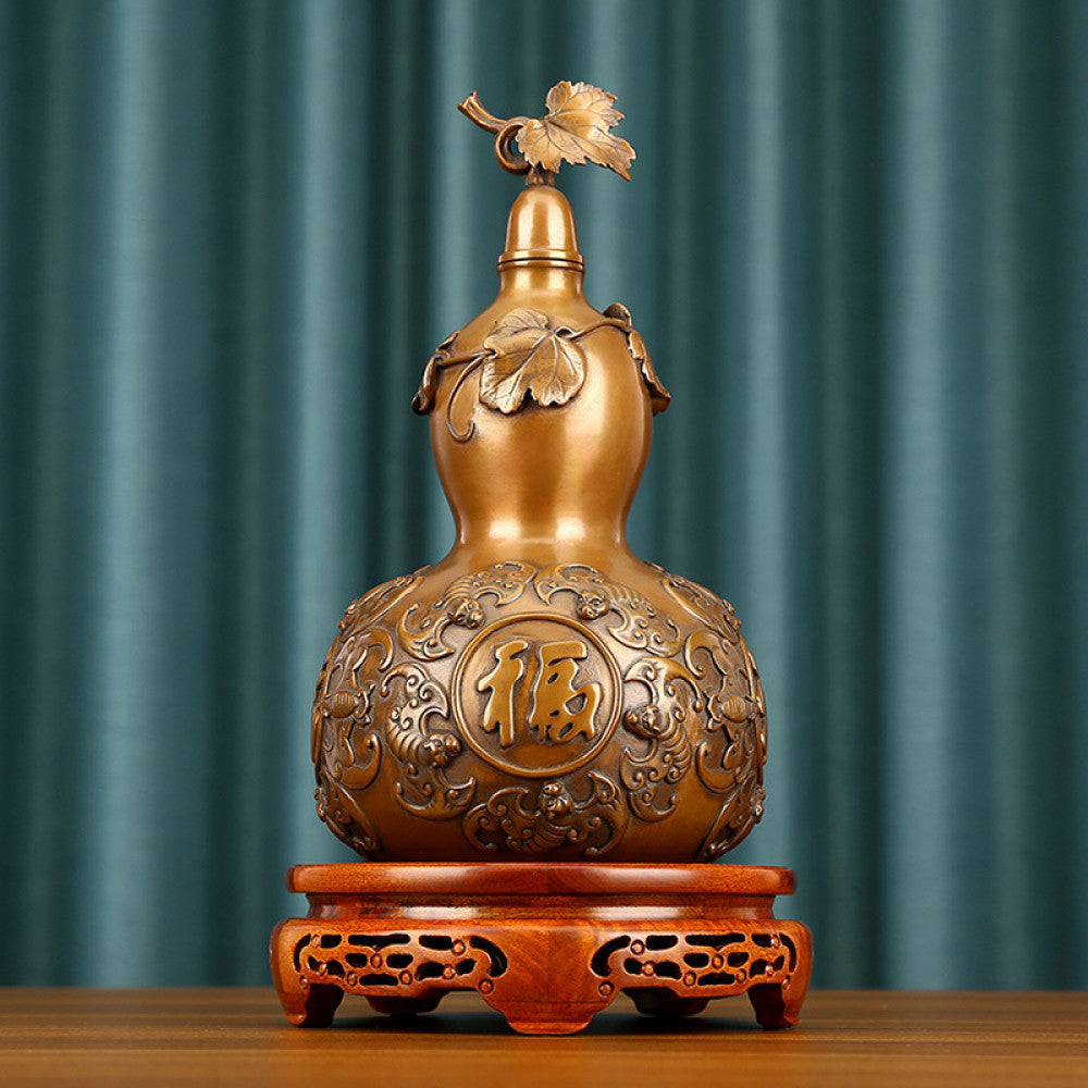 Traditional Chinese brass gourd decor with fortune characters and intricate carvings, placed on a wooden base against a teal curtain background 01