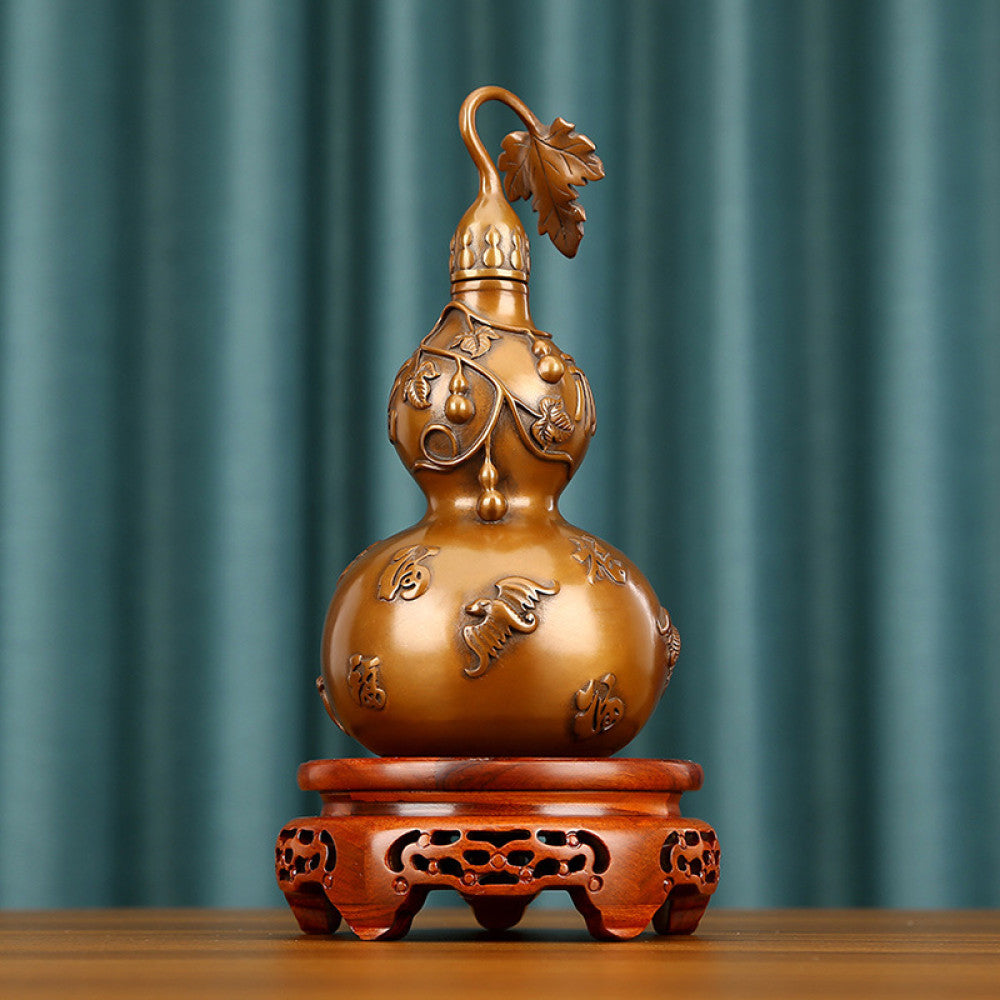 Traditional Chinese brass gourd decor with fortune characters and intricate carvings, placed on a wooden base against a teal curtain background 02