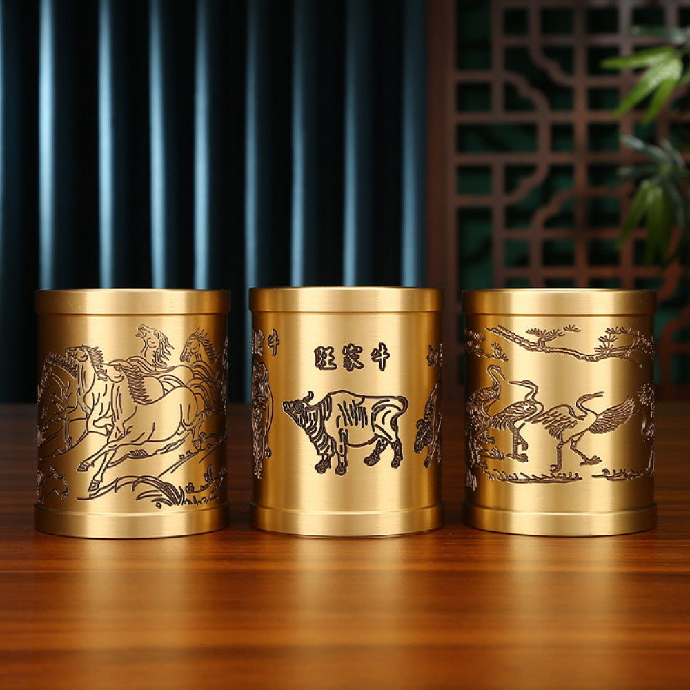 Three traditional Chinese brass pen holders with zodiac animal and Chinese character carvings, placed on a wooden table against a traditional interior background