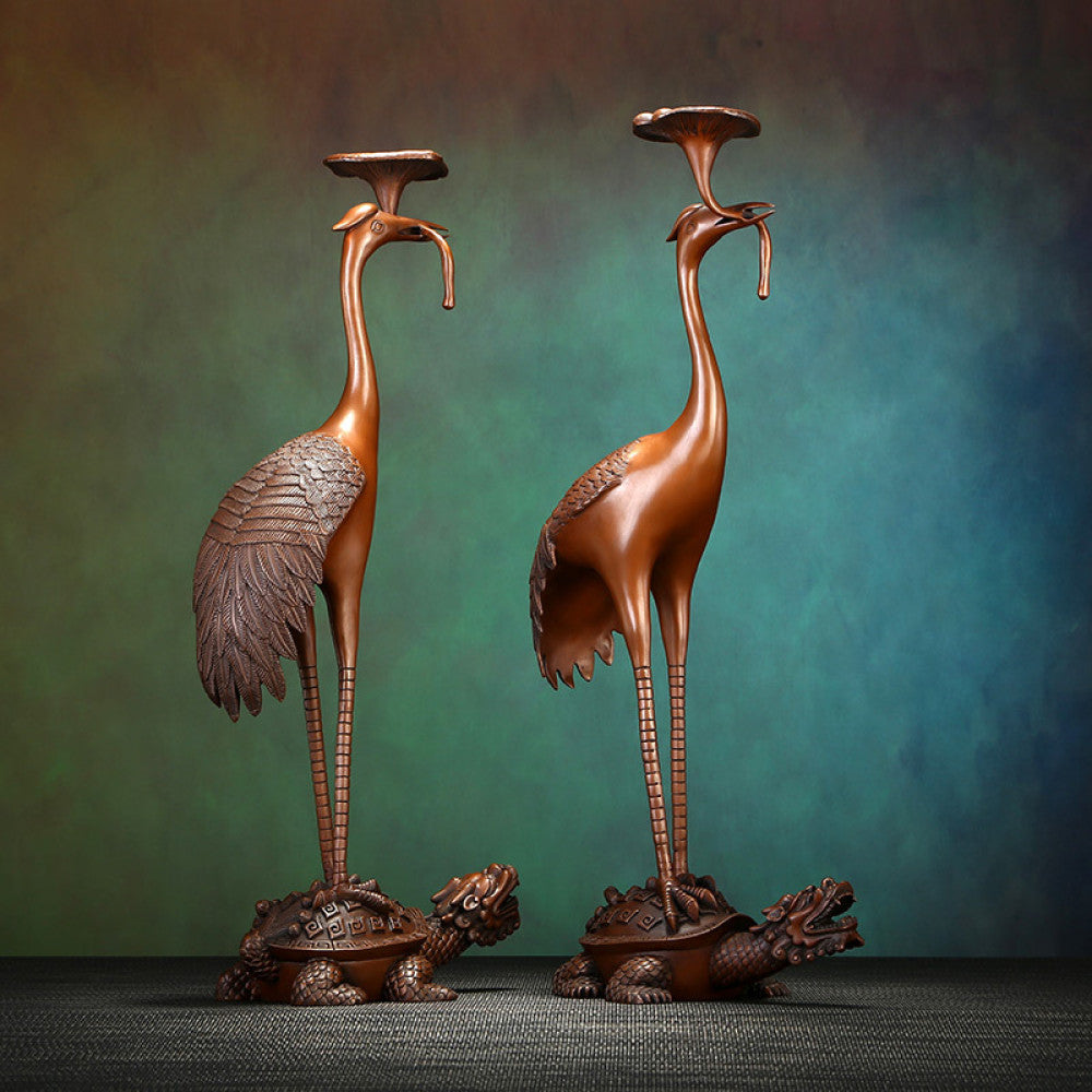 Pair of traditional Chinese bronze crane and tortoise candle holders, with cranes standing on tortoises, against a gradient teal - green background