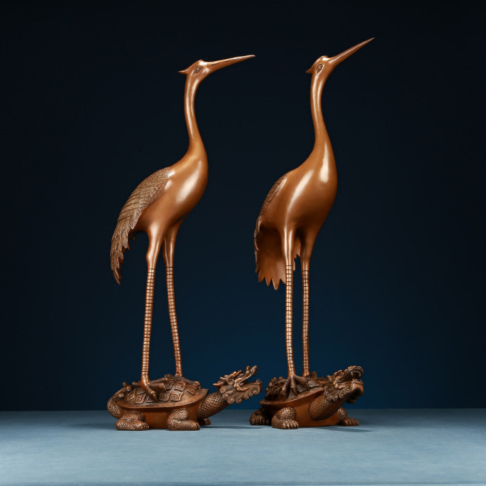 Pair of traditional Chinese bronze crane statues standing on tortoises, displayed against a dark blue background