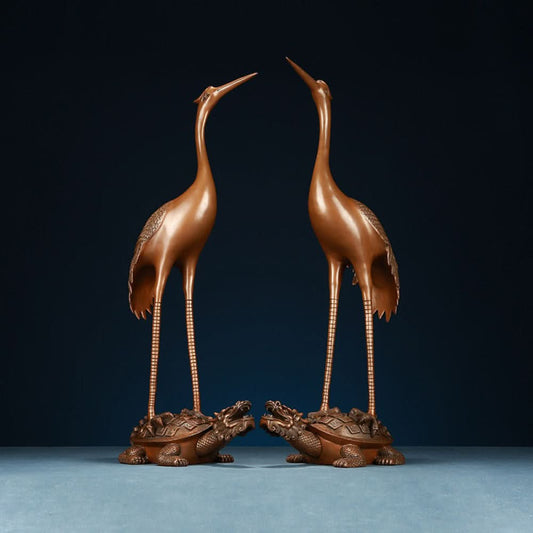 Pair of traditional Chinese bronze crane statues standing on tortoises, displayed against a dark blue background