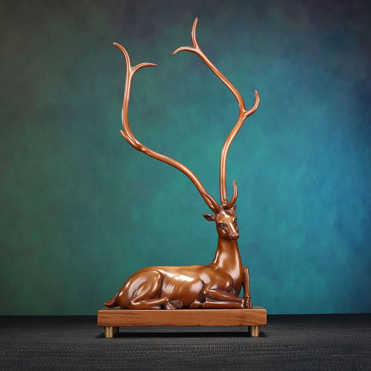 Traditional Chinese bronze deer statue with long antlers, lying on a wooden base against a teal and brown gradient background