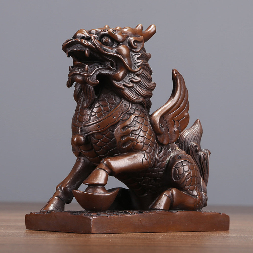 Traditional Chinese bronze Qilin statue with wings, standing on a yuanbao ingot, placed on a wooden base against a gray background